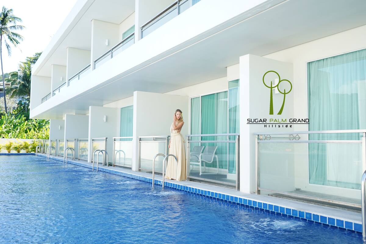 Un hotel moderno con piscina, una persona vestida y el nombre 'Sugar Palm Grand Hillside'.