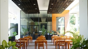 A modern indoor space with wooden tables and chairs arranged in rows, large windows, and potted plants. - Sugar Palm Grand Hillside (Karon)