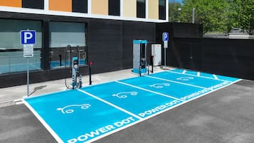 Un área de estacionamiento con espacios reservados para vehículos eléctricos, incluyendo una estación de carga.