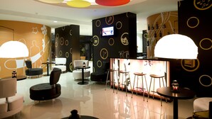 A modern lounge area with a bar, seating, and a TV screen. - Star Inn Porto (Porto)