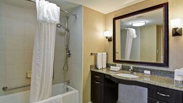 A modern bathroom with a bathtub, shower, vanity with a sink, and a large mirror.