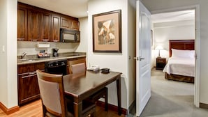 A compact hotel room with a kitchenette, a dining area, and a bedroom.