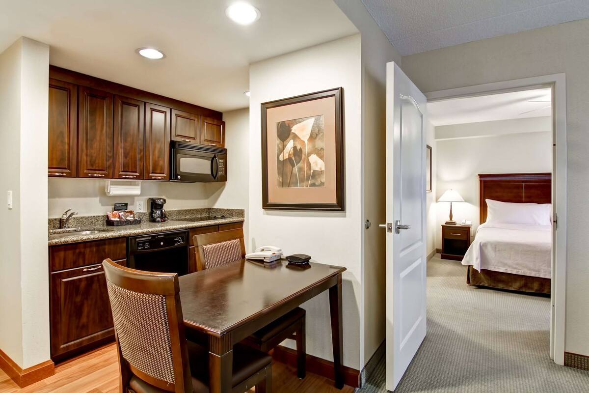 Une chambre d’hôtel compacte comprenant un coin cuisine, un espace repas et une chambre à coucher.