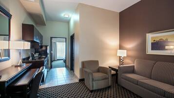 Een hotelkamer met een kitchenette, een eethoek, een bank, een stoel en een bed.