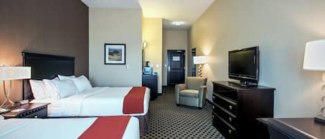 A hotel room with two beds, a television, a desk, and a chair.
