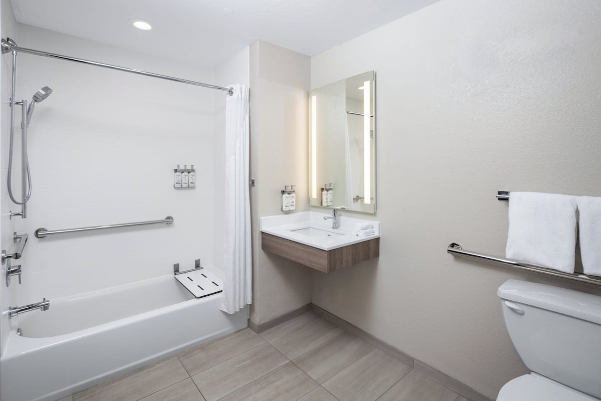 A modern bathroom with a bathtub, shower, sink, and toilet.