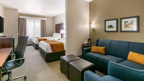 A hotel room with a bed, two bedside tables, a desk, a chair, a sofa, and two framed pictures on the wall.