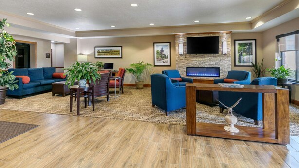 A spacious lobby with a fireplace, comfortable seating, and a large TV screen.