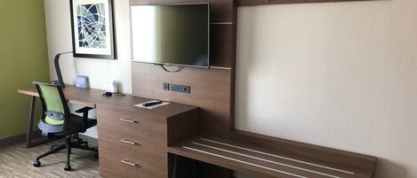A modern office space with a desk, chair, and mounted TV.