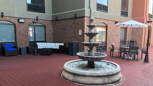 A courtyard with a stone fountain, outdoor seating, and a brick building. - Holiday Inn Express & Suites Franklin KY by IHG (Franklin)
