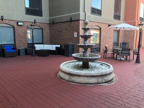 A courtyard with a stone fountain, outdoor seating, and a brick building. - Holiday Inn Express & Suites Franklin KY by IHG (Franklin)