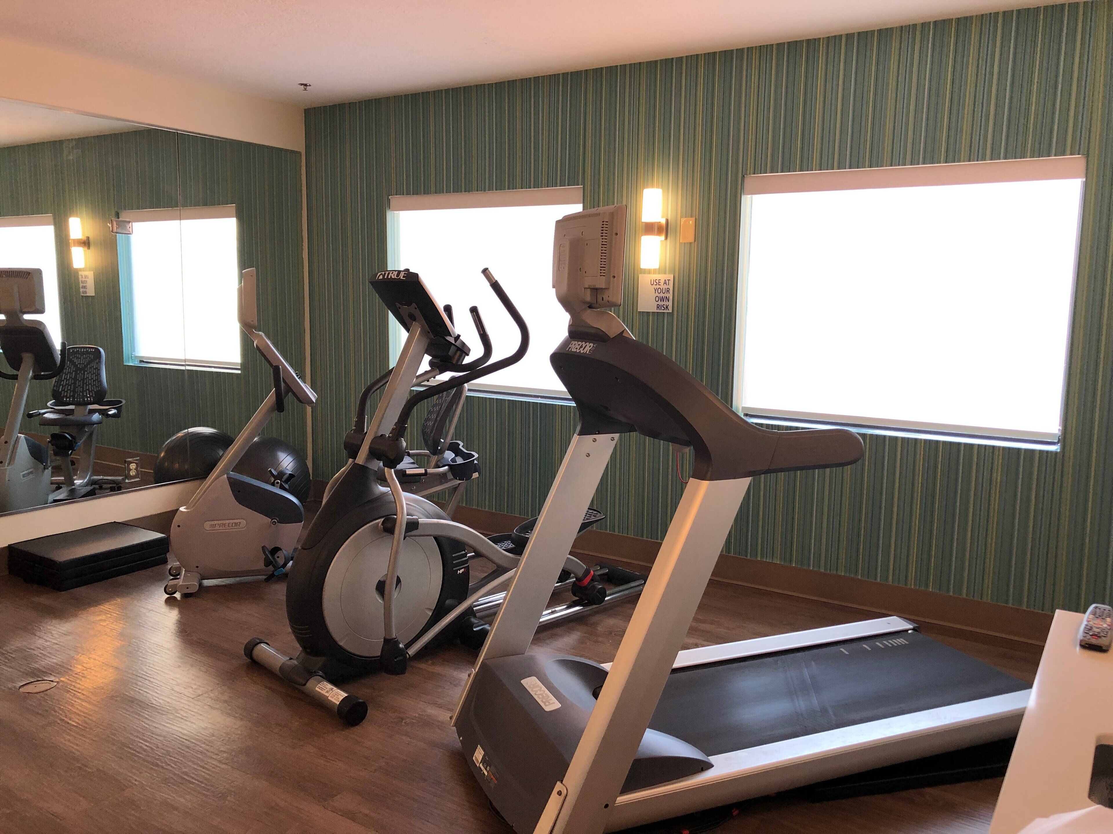 Une salle de sport équipée de tapis de course, de vélos d’appartement et de ballons d’exercice.