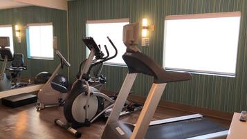 Une salle de sport équipée de tapis de course, de vélos d’appartement et de ballons d’exercice.