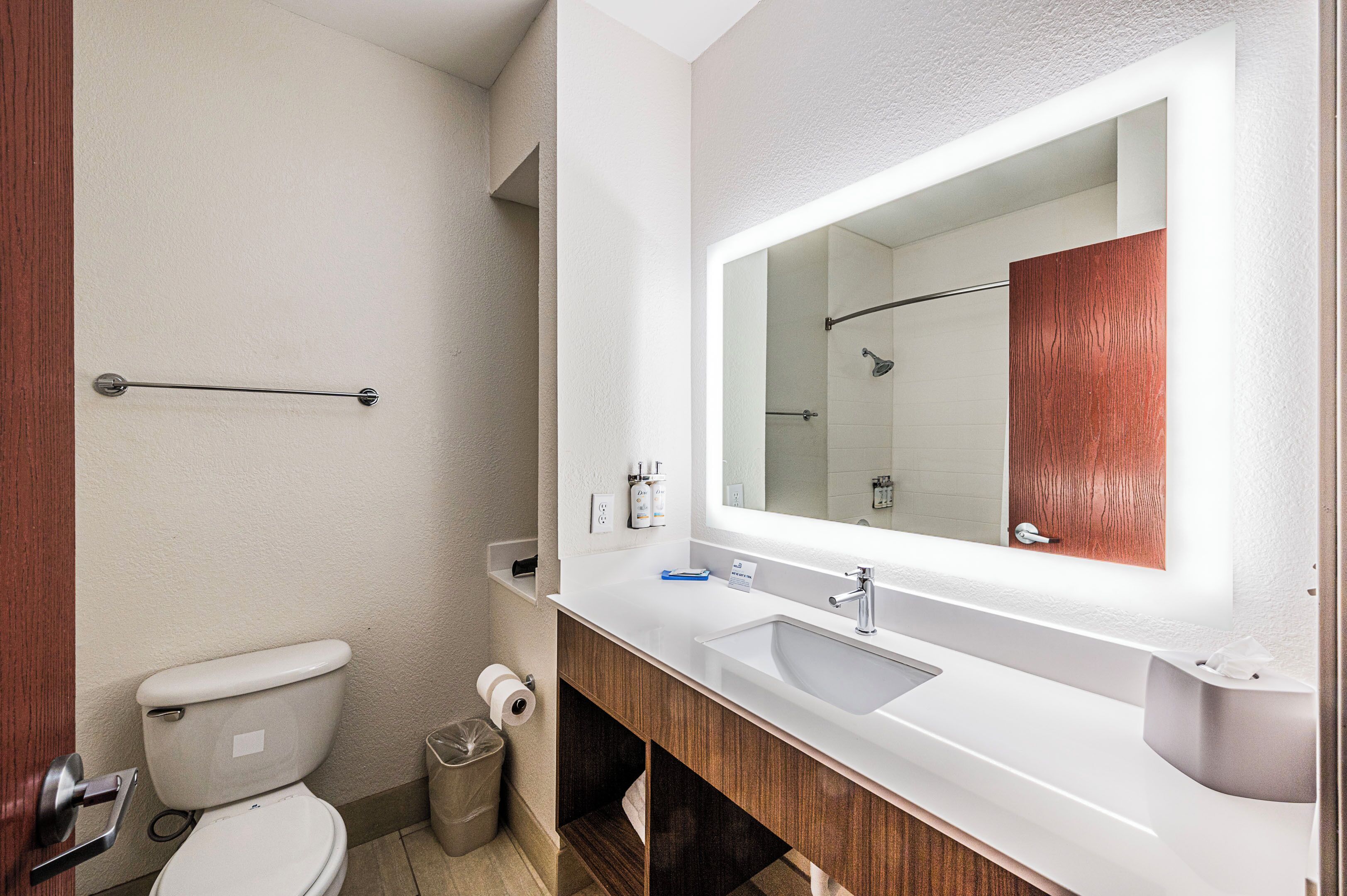 A modern bathroom with a toilet, sink, mirror, and towel rack.