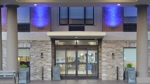 A building entrance with a stone facade, glass doors, and a bench outside. - Holiday Inn Express & Suites Franklin KY by IHG (Franklin)