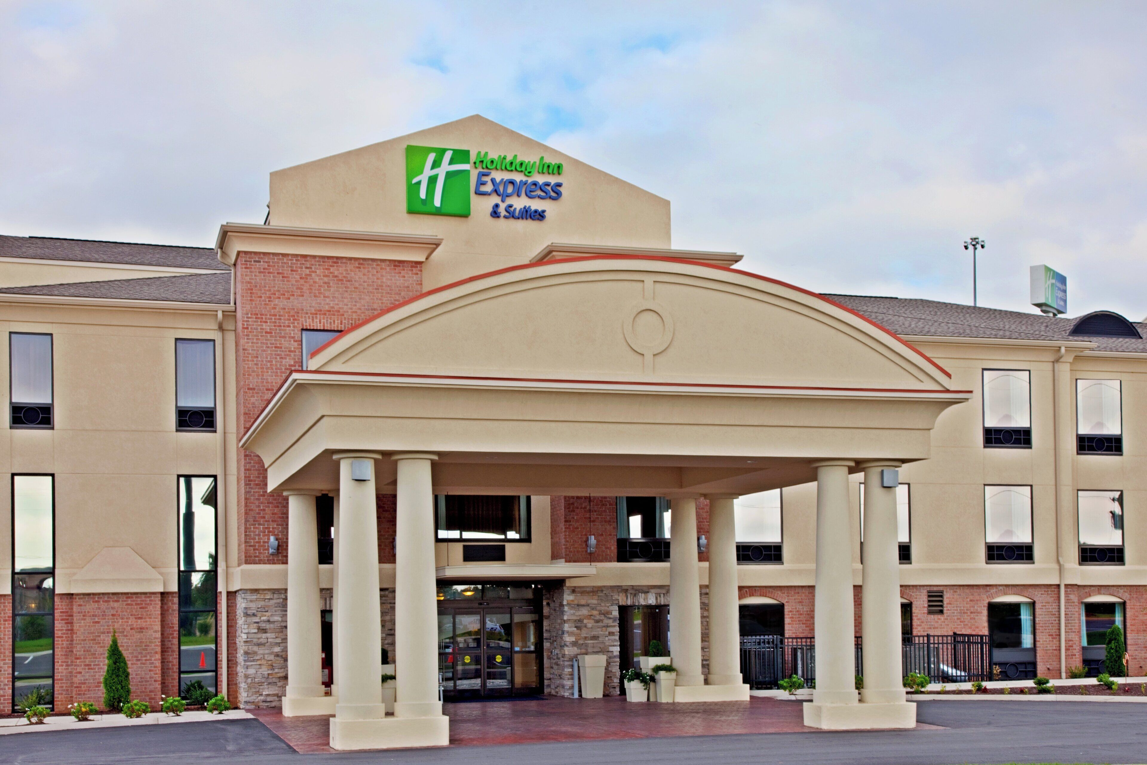 Een Holiday Inn Express & Suites gebouw met een overdekte ingang en een gevel van baksteen.