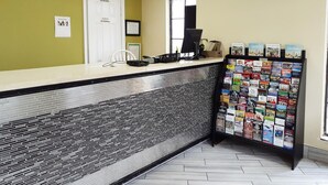 A reception area with a tiled counter, a computer, a phone, and a display of travel brochures.
