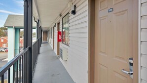 A hotel corridor with a covered balcony, a fire alarm box, and a door marked with the number 530.