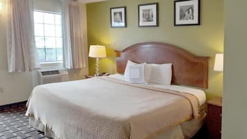 A hotel room with a large bed, a nightstand, a lamp, and three framed pictures on the wall.