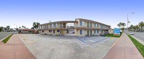 Hotel entrance with covered walkway and parking lot.