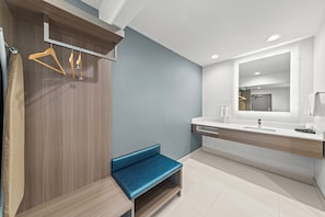 A modern bathroom with a bench, a mirror, and a towel rack.