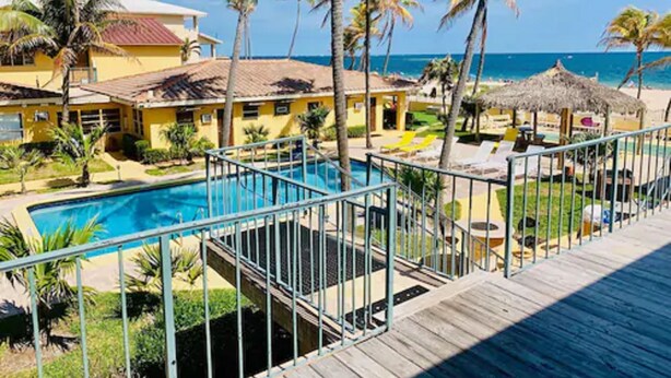 A resort with a swimming pool, palm trees, and a view of the ocean.