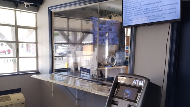 An ATM machine, a window with a view of the street, and a sign with rules. - Budget Inn and Suites (Mount Ephraim)