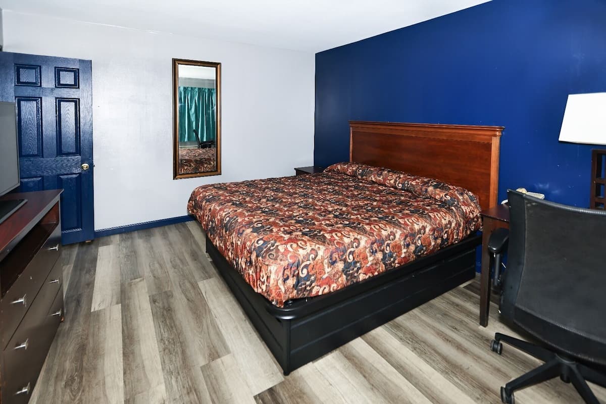A bedroom with a bed, a desk, and a chair.
