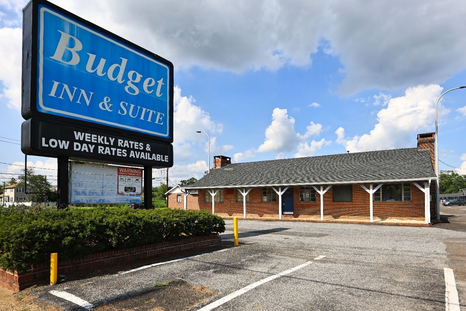 A Budget Inn & Suite sign with a brick building in the background.
