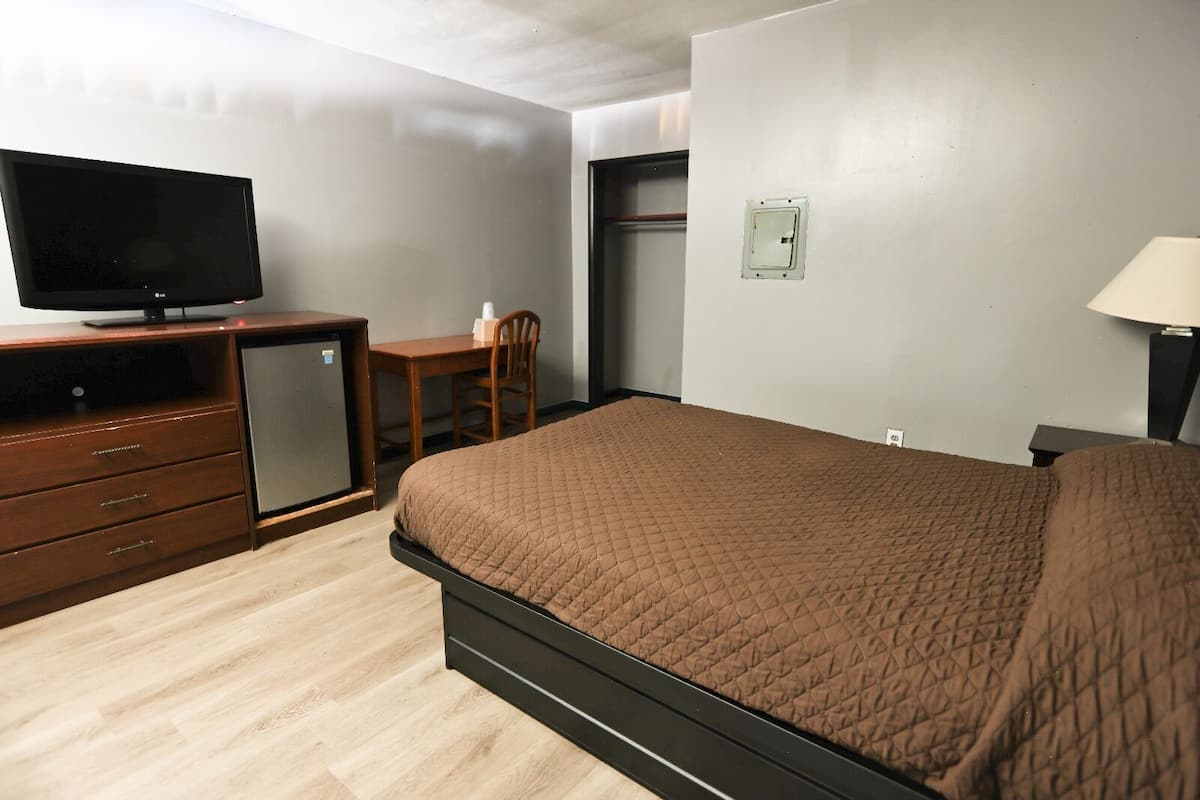 A hotel room with a bed, a dresser, a television, a desk, and a chair.