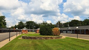 A motel with a central landscaped area, a parking lot, and a row of rooms with a covered porch. - Budget Inn and Suites (Mount Ephraim)