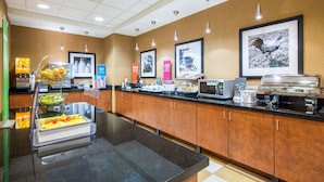 A modern kitchen with a black countertop, wooden cabinets, and various food items and appliances. - Hampton Inn & Suites Oklahoma City - South (Oklahoma City)