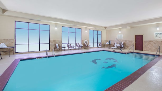 A large indoor swimming pool with clear blue water, surrounded by lounge chairs and a sunbed. - Hampton Inn & Suites Oklahoma City - South (Oklahoma City)