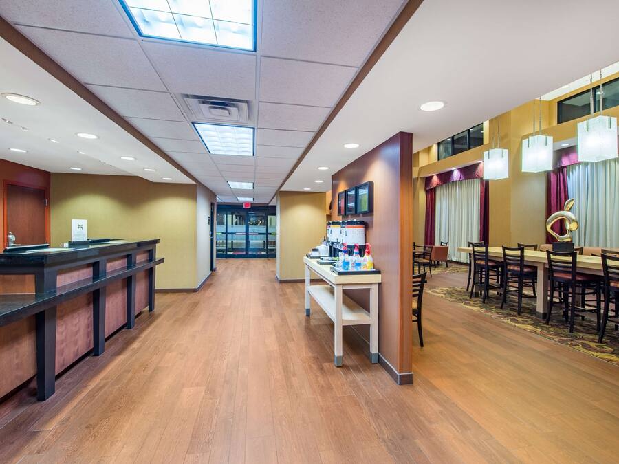 A hotel lobby with a reception desk, a dining area with a long table and chairs, and a carpeted floor.