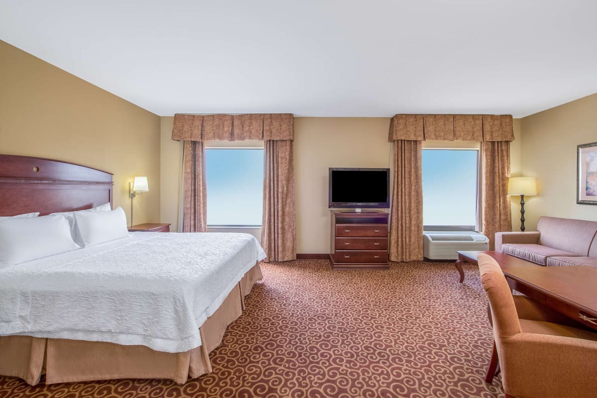 A hotel room with a large bed, a TV, a sofa, and a desk.