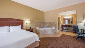 A hotel room with a large bed, a separate bathroom with a bathtub, a desk, and a chair. - Hampton Inn & Suites Oklahoma City - South (Oklahoma City)