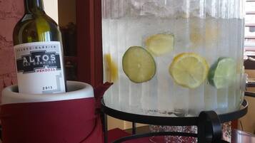 A glass jar with ice and lemon slices, a bottle of wine, and metal salt and pepper shakers on a table.