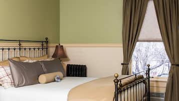 Un dormitorio con cama, radiador, ventana con cortinas y lámpara.
