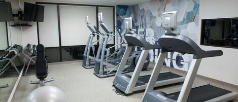 A gym with treadmills, exercise balls, and a mirrored wall.