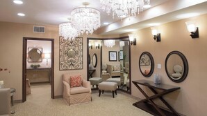 A well-lit room with a chandelier, a sofa, a chair, and a mirror on the wall.