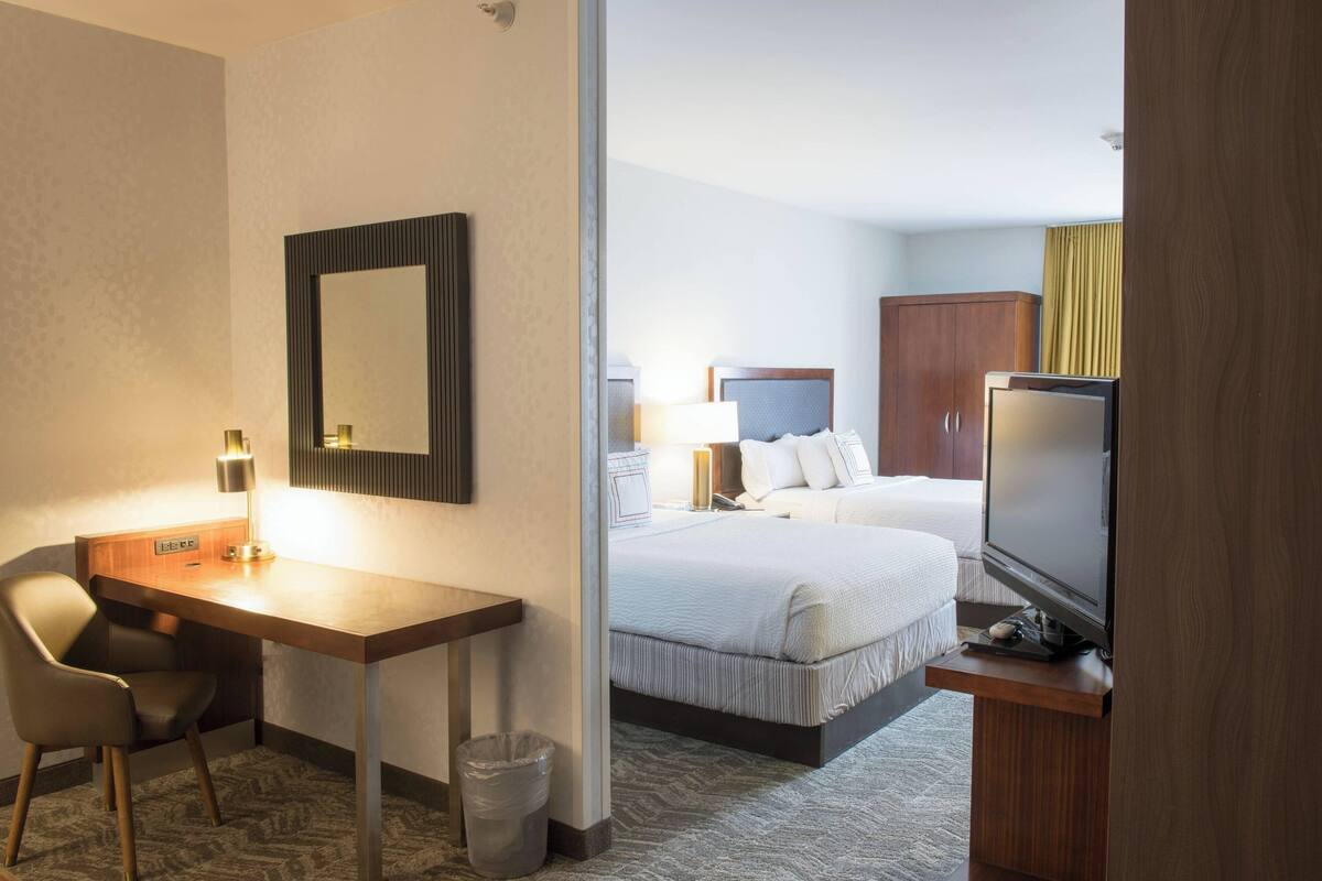A hotel room with a desk, chair, television, and a bed with a headboard.