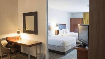 A hotel room with a desk, chair, television, and a bed with a headboard.