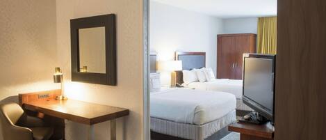 Habitación de hotel con escritorio, silla, televisor y cama con cabecero.
