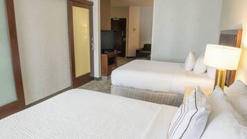 A hotel room with two beds, a television, and a desk with a computer.