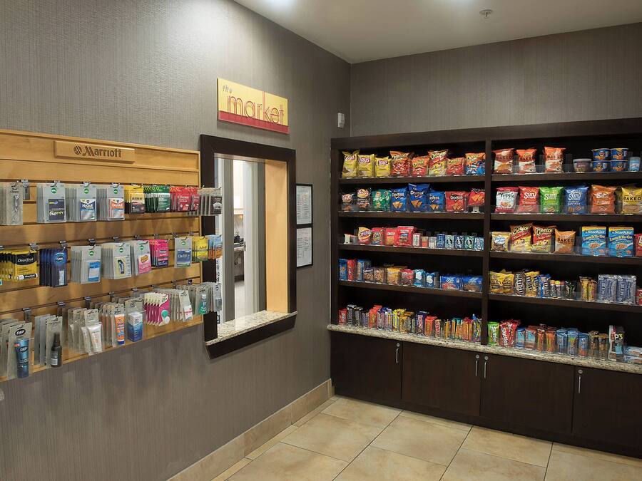 En hotellobby med en skylt som visar ordet ”Butik”, hyllor fyllda med snacks och hygienartiklar samt en ”Marriott”-skylt ovanför hyllorna.