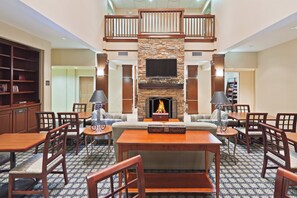 A spacious living area with a fireplace, a television mounted above it, and a library to the left.