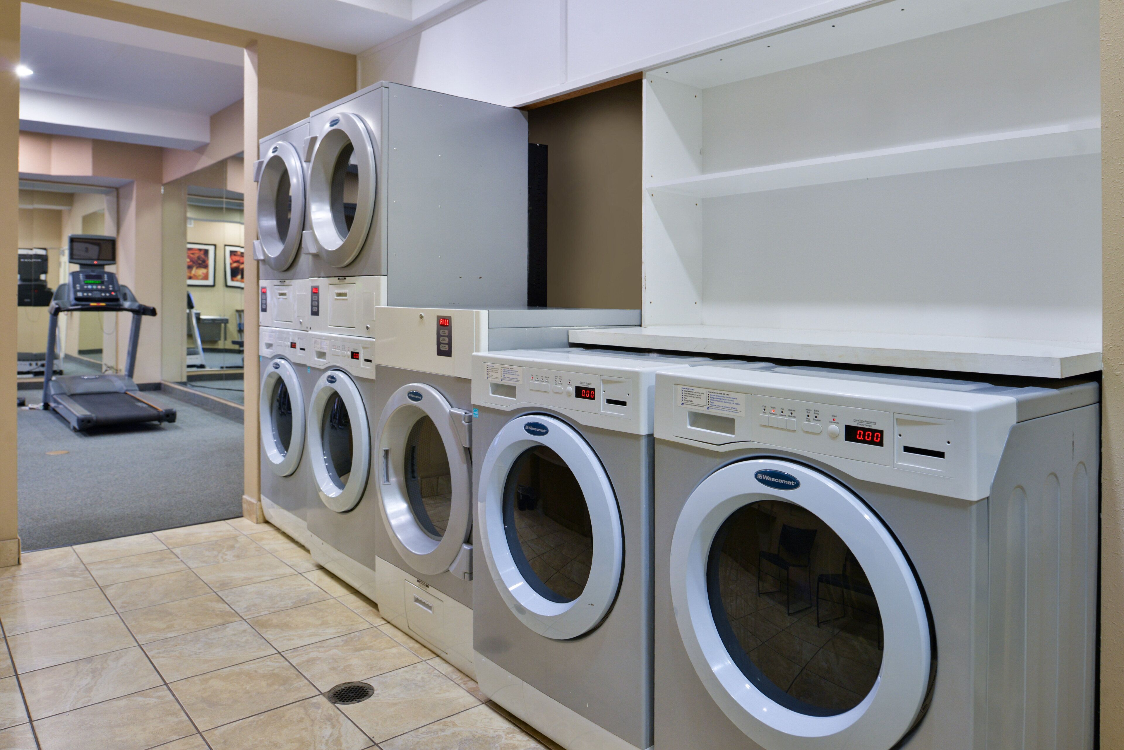 A laundry facility with multiple washing machines and a treadmill.