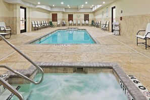 A swimming pool with a diving board and lounge chairs around it.