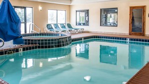 Una piscina interior con borde de azulejos, sillas de descanso y zona cubierta.