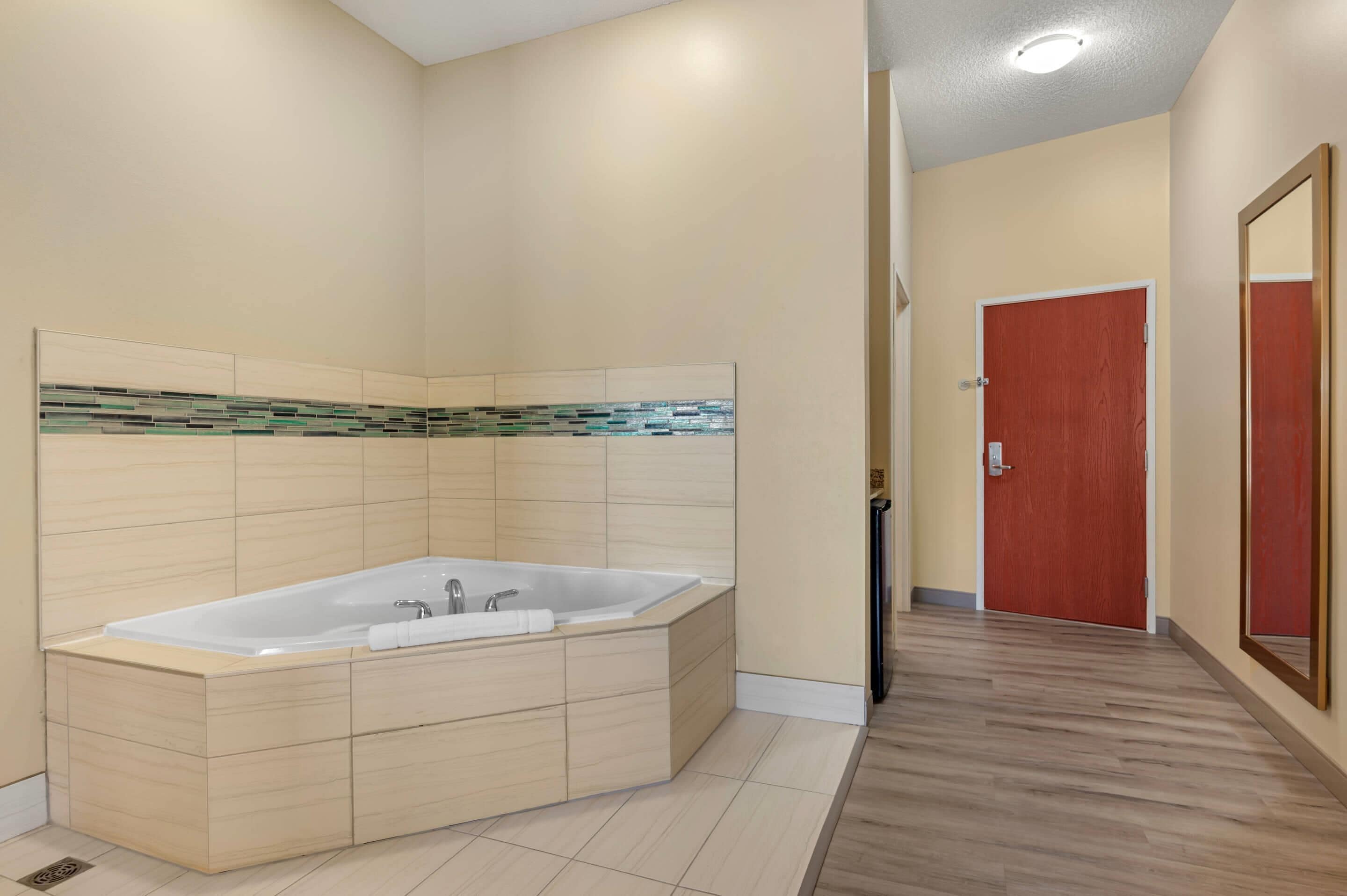 Une salle de bain moderne dotée d’une grande baignoire, de meubles en bois et d’un pare-feu en carreaux.